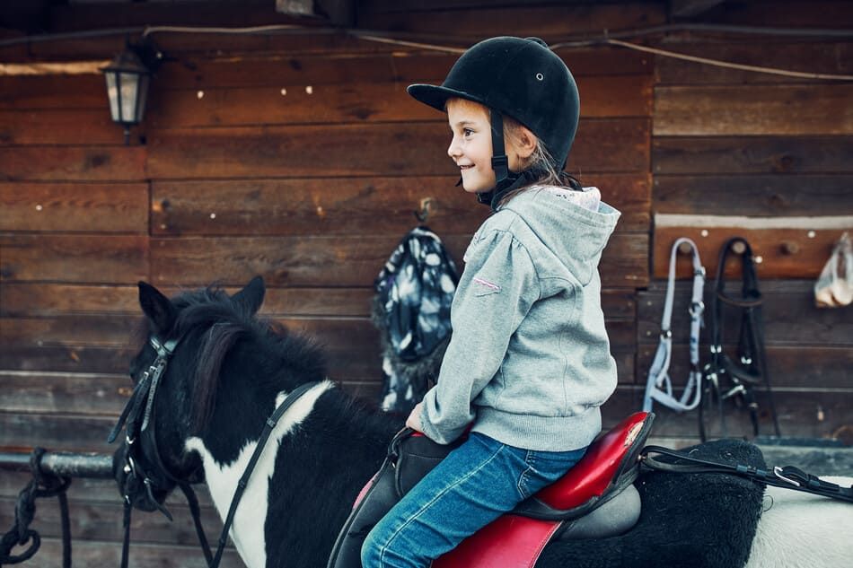 niña pequeña montando a caballo